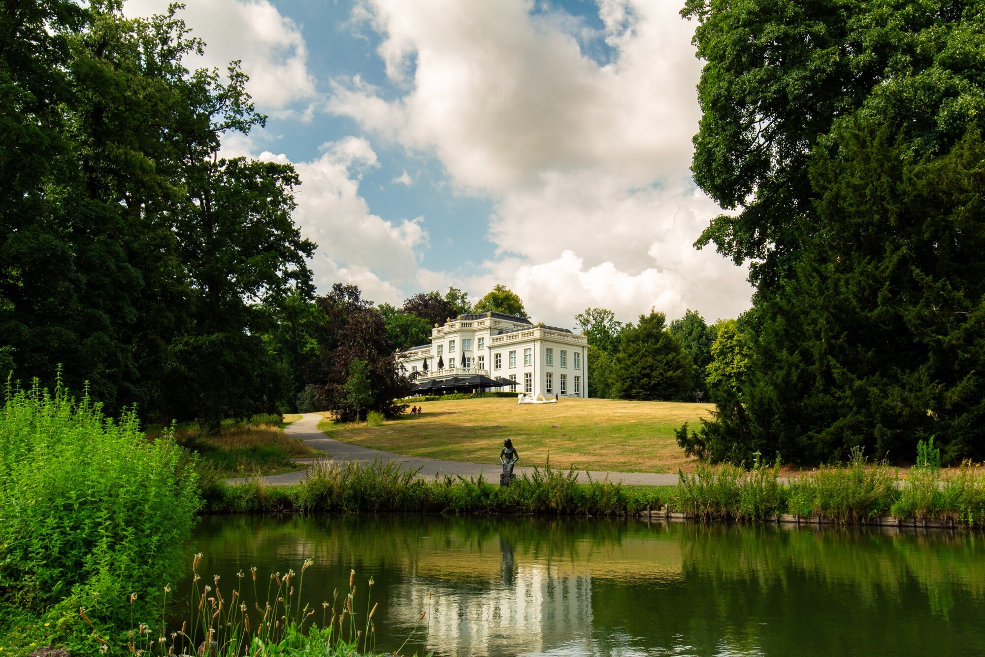 Huis Sonsbeek, omringd door groen en weerspiegeld in het water